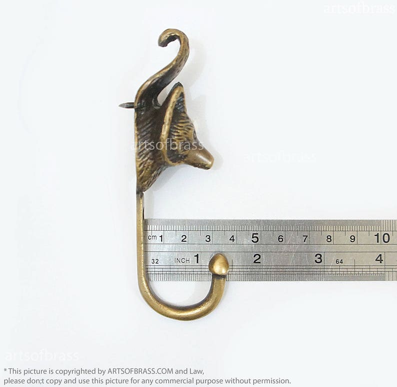 May include: Brass fox head wall hook with a 2 inch hook. The hook is measured with a ruler.