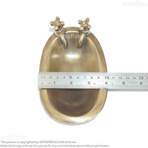 May include: A small, brass bathtub with two faucets. The bathtub is about 2 inches long and is made of solid brass. It is a decorative item and would be a great addition to any bathroom.