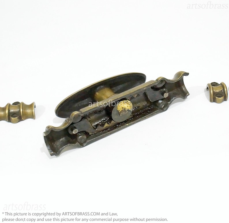 May include: Brass window latch with a decorative handle and a mechanism that is visible. The latch is in three pieces, with two separate pieces that attach to the main piece.