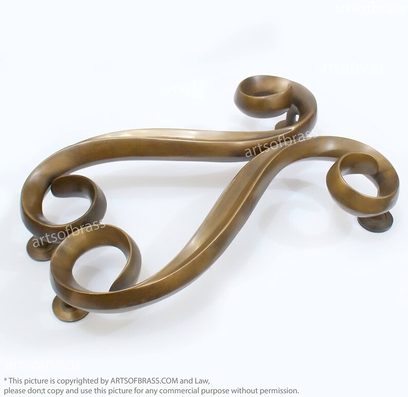 May include: A decorative brass door handle with a unique, swirling design. The handle is made of solid brass and has a polished finish.
