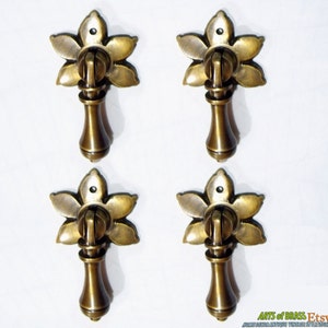 May include: Four antique brass cabinet pulls with a floral design. Each pull has a round knob and a decorative flower-shaped base.