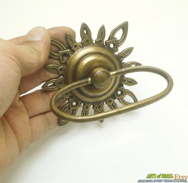 May include: A brass towel ring with a decorative sunburst design. The ring is made of solid brass and has a polished finish.