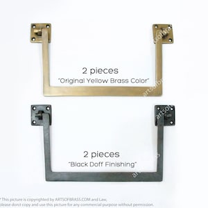 May include: Two pairs of brass door hinges, one pair in original yellow brass colour and the other pair in black doff finish. Each hinge is a right angle with a square plate on the top and a long arm extending down.