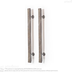 Può includere: Due maniglie per porte in legno rustico con pomelli in metallo nero. Le maniglie sono in legno con una finitura naturale e hanno una forma rettangolare.