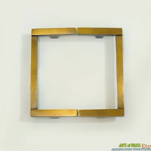 Pode incluir: Um conjunto de quatro puxadores de armário de latão, cada um com uma forma retangular e um design ligeiramente curvo. Os puxadores são em latão polido.