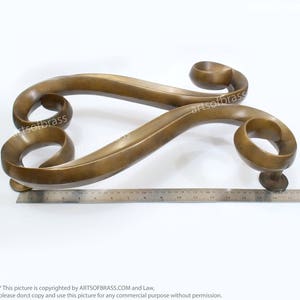 May include: A pair of ornate brass door handles with a swirling design. The handles are approximately 17 inches long.