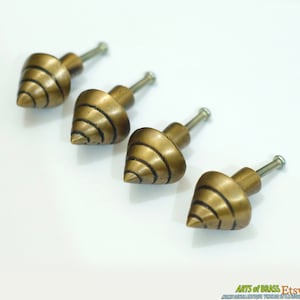 Può includere: Quattro pomelli per armadi in metallo dorato con un design a spirale appuntito. I pomelli hanno un attacco a vite.