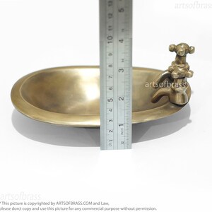 May include: A small brass bathtub with a faucet and two knobs. The bathtub is 5 inches long and is made of solid brass.
