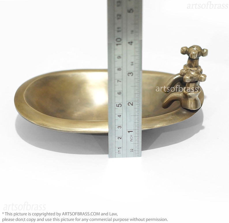 May include: A small brass bathtub with a faucet and two knobs. The bathtub is 5 inches long and is made of solid brass.