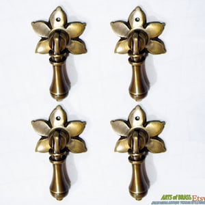 May include: Four antique brass cabinet pulls with a floral design. Each pull has a round knob and a decorative flower-shaped base.