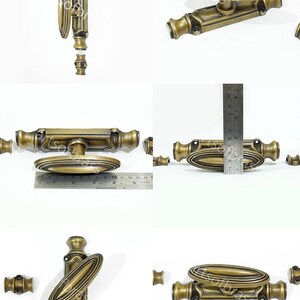 May include: Antique brass espagnolet lock with a large oval handle. The lock is shown in various positions with a ruler for scale. The lock is approximately 5 inches long.