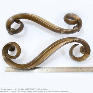 May include: Two ornate brass door handles with a swirling design. The handles are approximately 15 inches long.
