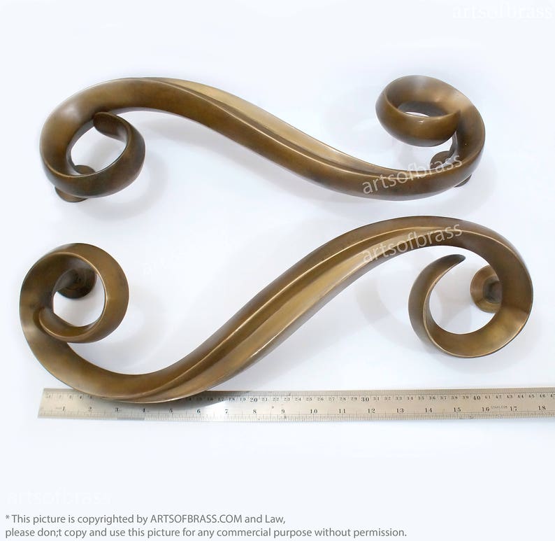 May include: Two ornate brass door handles with a swirling design. The handles are approximately 15 inches long.