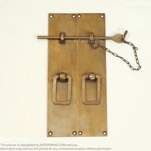 Peut inclure: Une paire de poignées de porte en laiton massif de forme rectangulaire avec un sommet arrondi. Les poignées sont fixées à une paire de plaques rectangulaires avec un loquet décoratif et une chaîne.