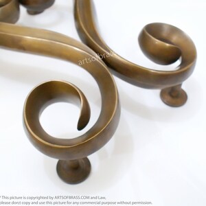 May include: A pair of ornate brass door handles with a swirling design. The handles are made of solid brass and have a polished finish.