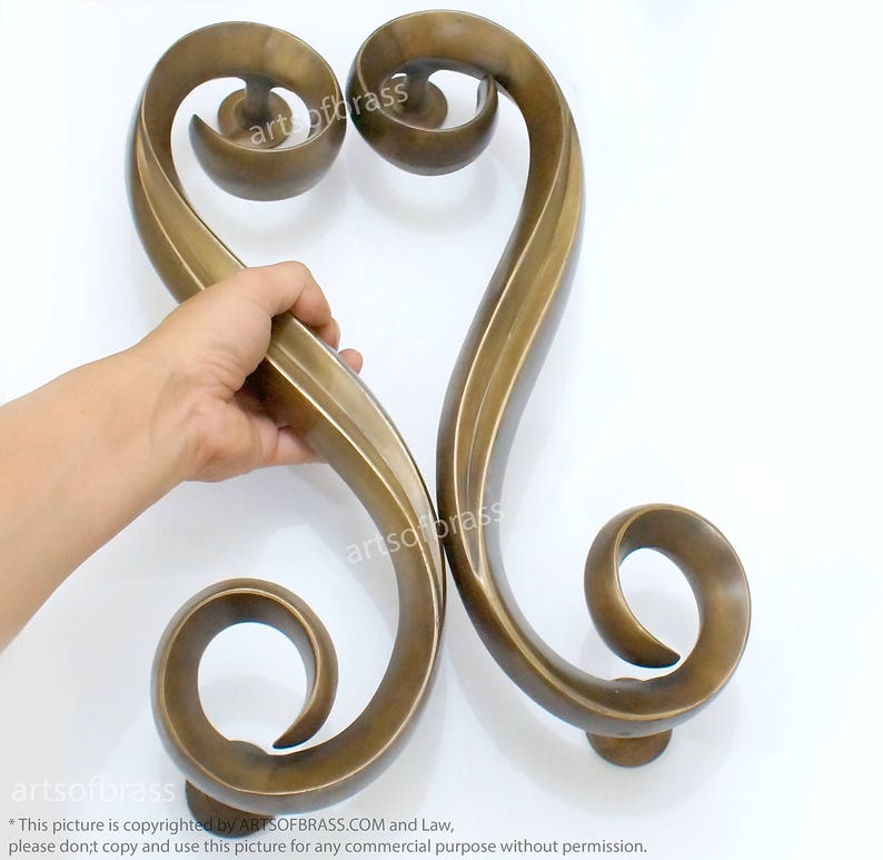May include: A pair of ornate, gold-toned, metal door handles in the shape of a heart. The handles are intricately designed with swirling patterns and have a smooth, polished finish.