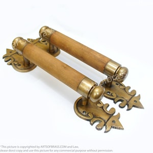 May include: A pair of ornate brass door handles with wooden grips. The handles feature a decorative design with intricate details.