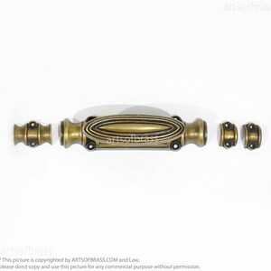 May include: A brass door latch with an oval-shaped handle and two round knobs. The latch is in a polished brass finish.