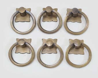 Puede incluir: Seis tiradores de anillo de latón antiguo con base cuadrada. Los tiradores tienen un acabado liso y envejecido y son perfectos para agregar un toque de encanto vintage a los muebles o armarios.