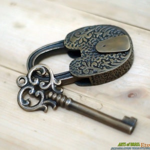 May include: An ornate brass padlock with a key. The padlock has a heart-shaped design with intricate floral patterns. The key is also made of brass and has a decorative design.