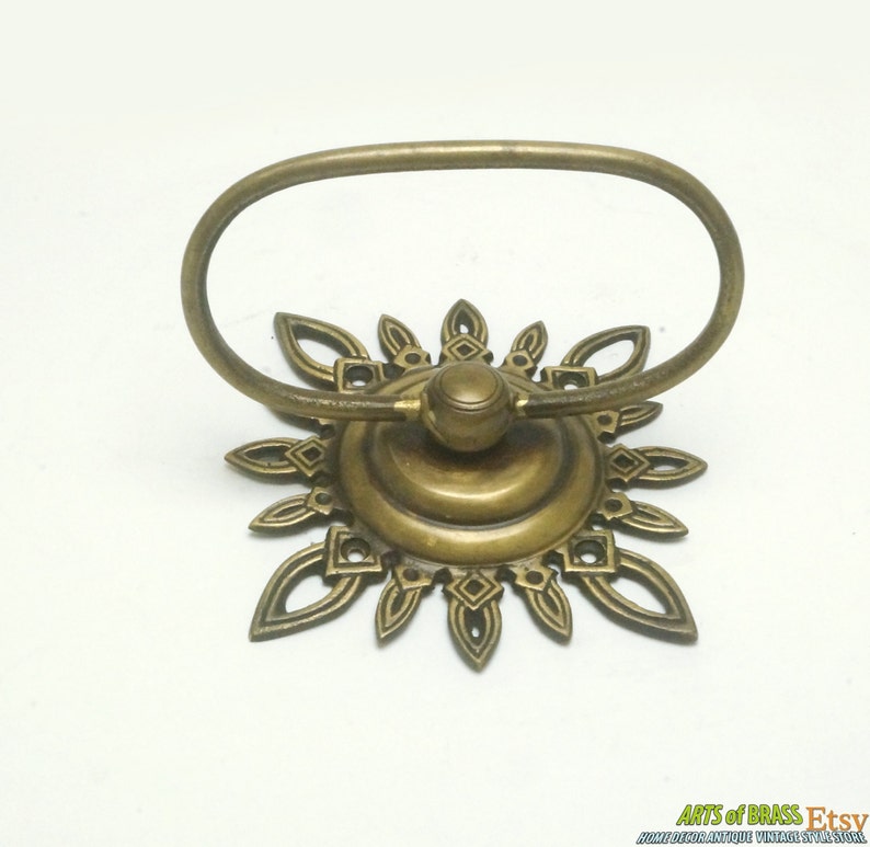 May include: A brass towel ring with a decorative sunburst design. The ring is oval shaped and has a smooth, polished finish.