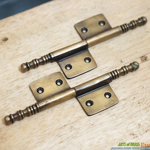 Peut inclure: Deux charnières anciennes en laiton avec un design décoratif et cannelé. Les charnières sont en excellent état et ont une patine chaude et vieillie.