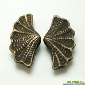 Peut inclure: Deux pièces décoratives en laiton antique avec un motif en forme d'éventail. Les pièces sont finement détaillées avec une surface texturée.