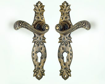 May include: A pair of antique brass door handles with ornate designs. The handles feature a keyhole and a decorative lever. The handles are in excellent condition and would be a beautiful addition to any home.