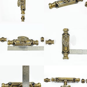 May include: Antique brass espagnolet lock with a small round knob. The lock is about 4 inches long and has a decorative design. The lock is made of metal and has a polished finish.