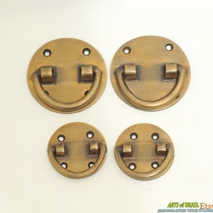 May include: Four brass drawer pulls with rounded edges and a D-shaped handle. The pulls are different sizes and have a polished finish.