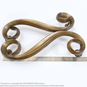 May include: A pair of ornate, gold-toned door handles with a decorative, swirling design. The handles are made of metal and have a polished finish.