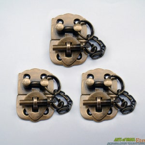 Puede incluir: Tres cierres de pestillo de latón antiguo con cadenas. Cada cierre tiene un diseño en forma de corazón y una pequeña perilla en la parte superior. Los cierres son perfectos para agregar un toque vintage a cualquier proyecto.