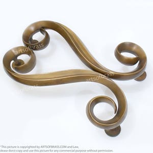 May include: A pair of ornate brass door handles with a heart-shaped design. The handles are made of a single piece of metal and have a smooth, polished finish.
