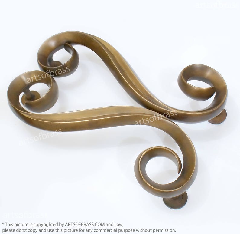 May include: A pair of ornate brass door handles with a heart-shaped design. The handles are made of a single piece of metal and have a smooth, polished finish.
