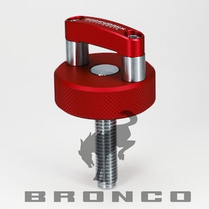 May include: Red metal screw-on cap with a black magnet and a silver loop handle. The cap has the text "ROCKWORX" and "CALIFORNIA" on it. The screw is silver and has a threaded design. The text "BRONCO" is printed in black below the screw.