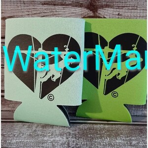May include: Two green and light green foam can coolers with a black heart design featuring a silhouette of a person climbing a rope. The heart has the word "Waterman" written across it.