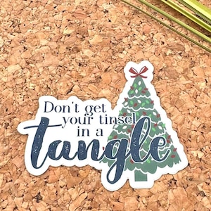 May include: A white sticker with a blue and green Christmas tree and the text "Don't get your tinsel in a tangle".
