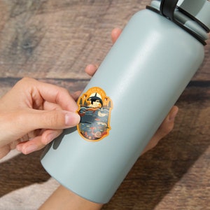 May include: A blue water bottle with a sticker of an orca whale and other sea creatures. The sticker says "Orcas Island, Washington State" in a yellow circle.
