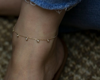 May include: A delicate gold anklet with a chain and small dangling diamonds.