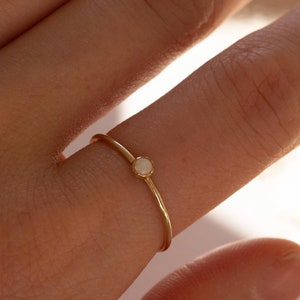 May include: A delicate gold ring with a small white opal gemstone.