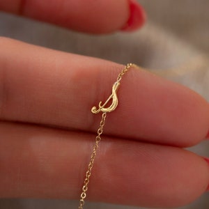 May include: A delicate gold chain necklace with a small, cursive letter 'S' pendant.