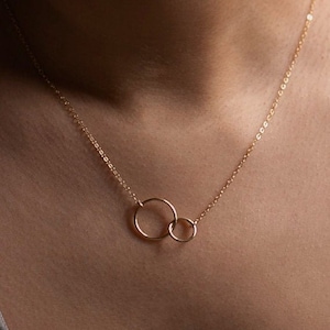 May include: A gold chain necklace with two interlocking circles as a pendant.
