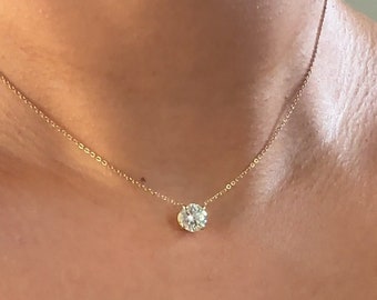 May include: A delicate gold chain necklace with a single, round, clear gemstone pendant.