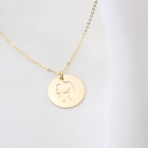 May include: A gold necklace with a round pendant featuring a line drawing of a female figure.