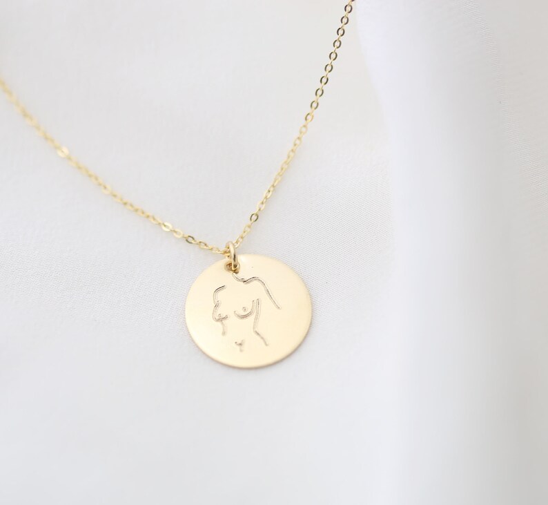 May include: A gold necklace with a round pendant featuring a line drawing of a female figure.