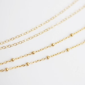 May include: Two gold chains, one with small round beads and one with a more traditional link design.