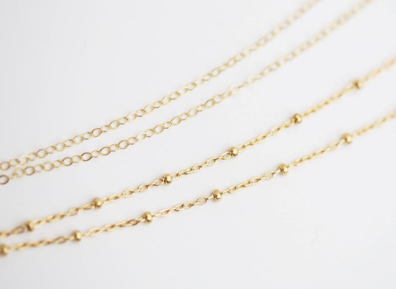 May include: Two gold chains, one with small round beads and one with a more traditional link design.