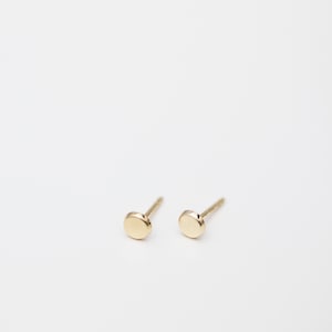 May include: A pair of small, round, gold stud earrings.