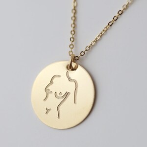 May include: A gold necklace with a round pendant featuring a line drawing of a person's torso.