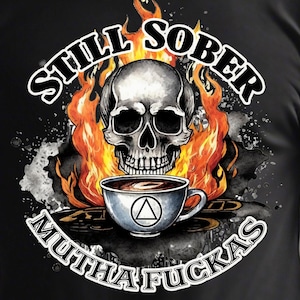 May include: Black t-shirt with a graphic design of a skull in flames holding a coffee cup with a triangle symbol. The text "Still Sober Mutha Fuckas" is written around the skull.